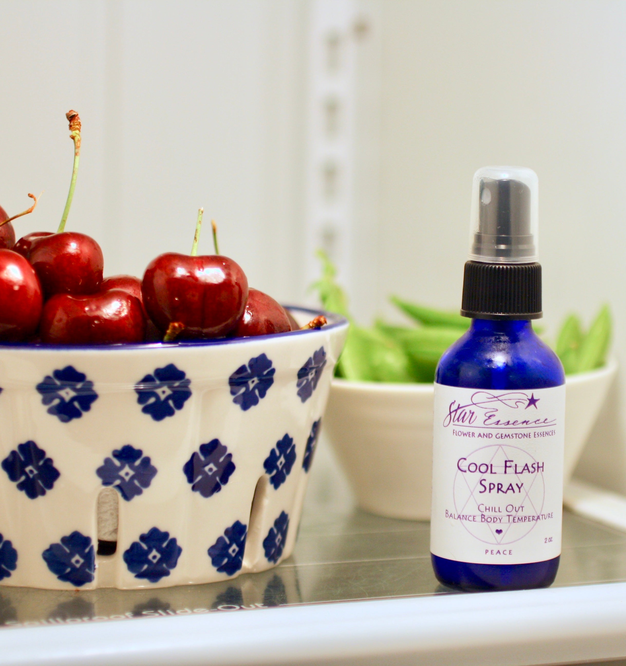 Cool Flash Spray essence bottle next to bowl of cherries representing refreshing energy healing and holistic medicine