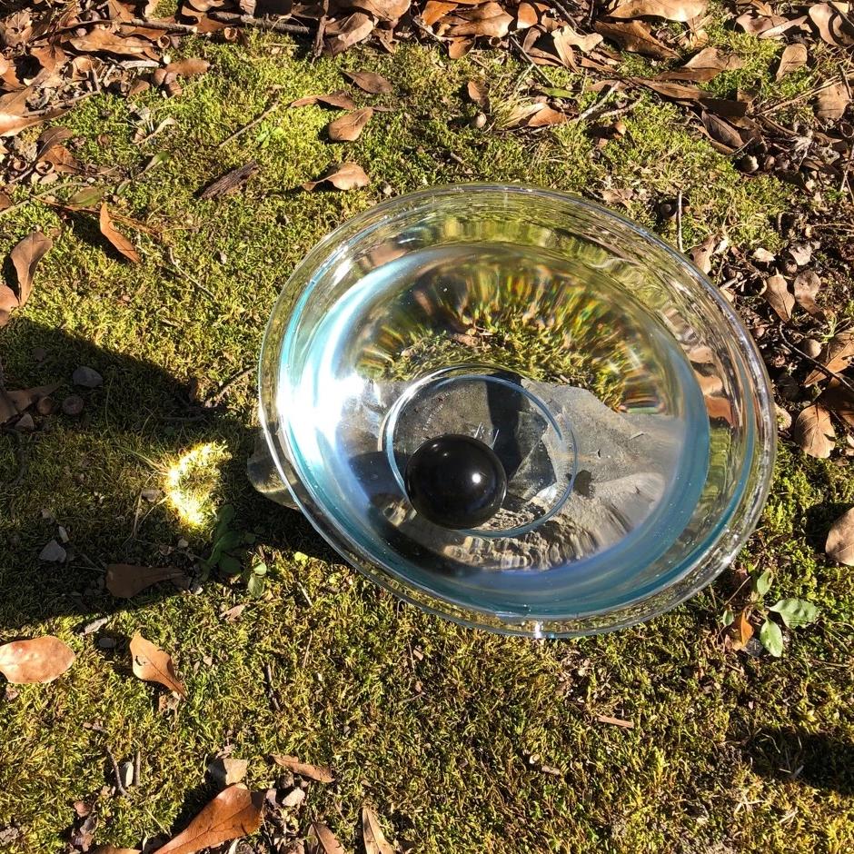 Shungite gemstone essence stone in a bowl of water for energy healing, holistic medicine, and spiritual wellness